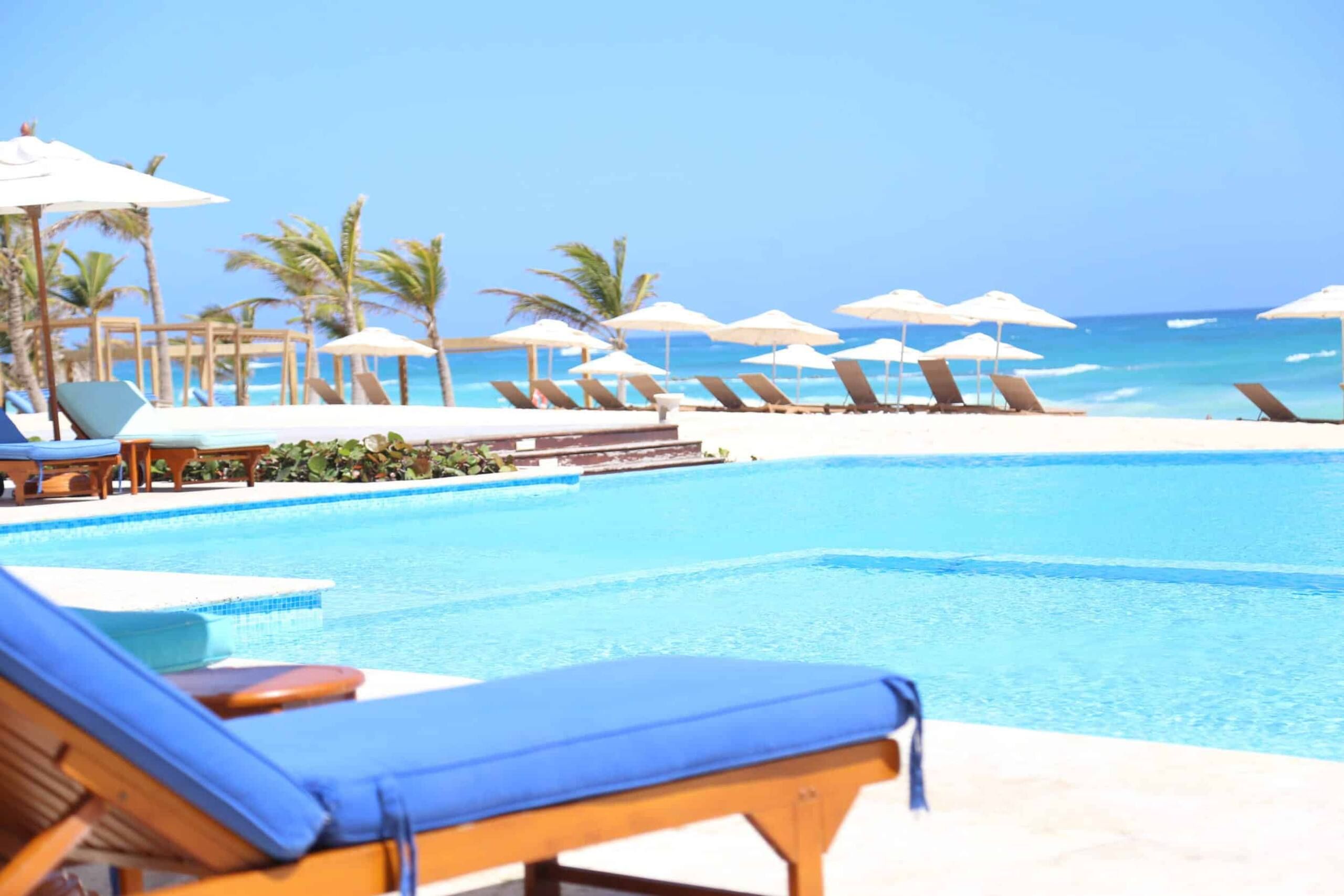 Blue lounger beside the beach club pool with the Caribbean Sea behind